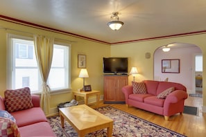 A living room with a pink sofa, a wooden coffee table, and a television on a wooden cabinet. - Lead Home w/ Free Wifi ~ 5 Mi to Terry Peak! (Lead)