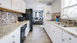 Una cucina moderna con mobili bianchi, un frigorifero nero e piastrelle a parete.