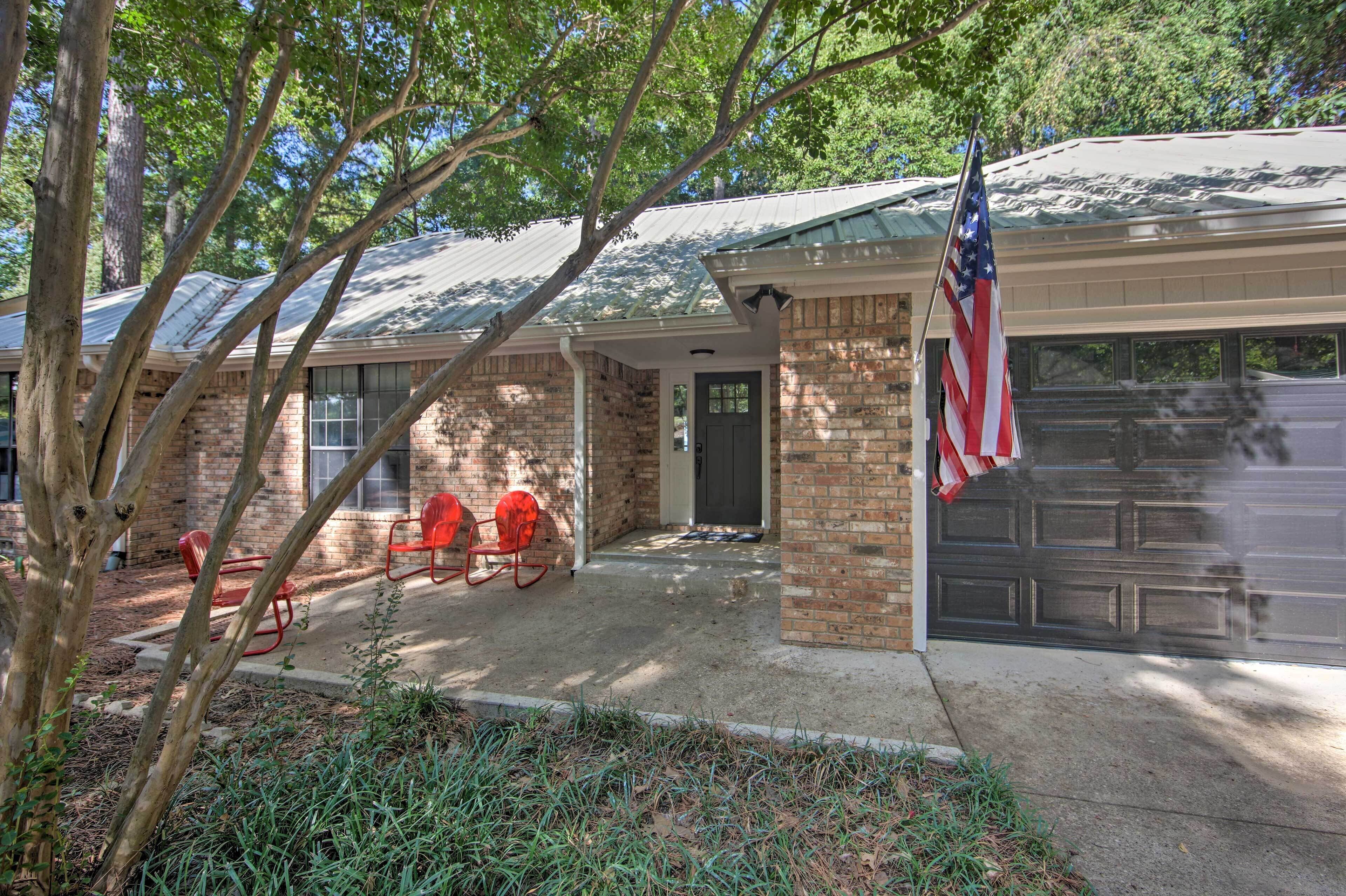 A brick house with a garage door, a covered porch, and an American flag.