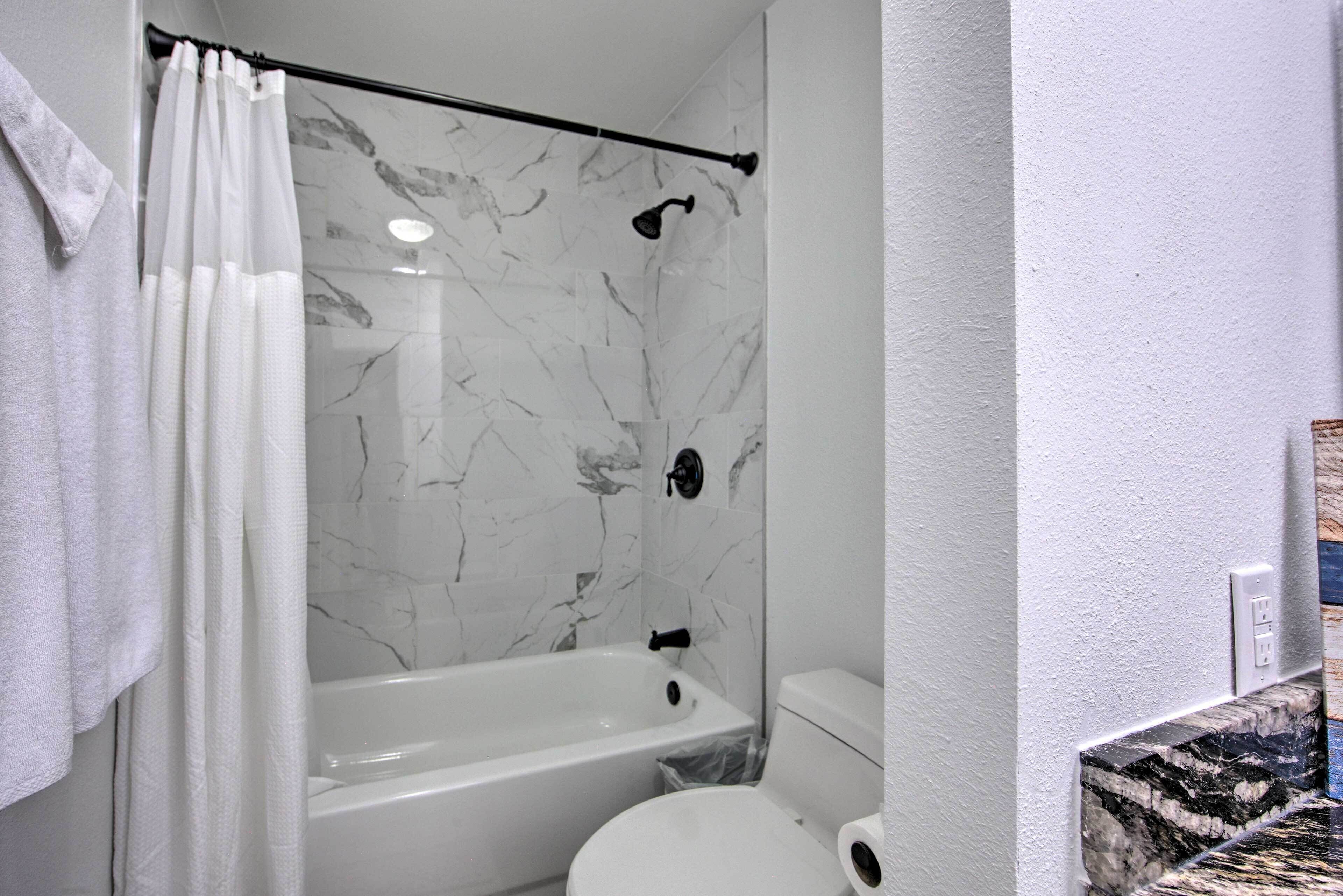 Une salle de bain avec une baignoire, des toilettes et des murs en marbre.