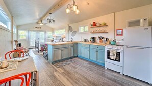Una cucina con pavimento in legno, un'isola centrale, un fornello, un forno a microonde e un frigorifero.
