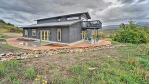 Una casa moderna a due piani con un portico coperto e un giardino curato.