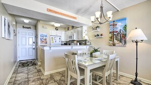A kitchen with white cabinets, a microwave, and a dining area with a glass table and white chairs. - Ocean Views & Pool Access: Myrtle Beach Condo! (Myrtle Beach)