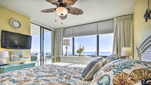 A bedroom with a large bed, a ceiling fan, a flat-screen TV, a window with curtains, and a view of the ocean. - Ocean Views & Pool Access: Myrtle Beach Condo! (Myrtle Beach)