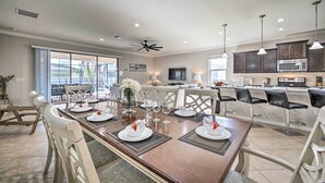 A modern kitchen with dark cabinets, a microwave, and a dining area with a wooden table set for six. - Kissimmee Retreat With Private Pool & Spa (Kissimmee)