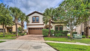 A two-story house with a garage, surrounded by palm trees and a well-maintained lawn. - Kissimmee Retreat With Private Pool & Spa (Kissimmee)