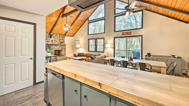 A kitchen with a wooden countertop, stone backsplash, and a dining area with a table and chairs. - Game Room, Fire Pit & Deck: Spacious Poconos Home! (Lake Harmony)