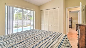 A bedroom with a large bed, sliding glass doors to a patio, and a walk-in closet. - Coastal Getaway w/ Pool: 6 Mi to St Pete Beach! (St. Petersburg)