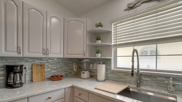 A kitchen with white cabinets, a built-in stove, a coffee maker, a blender, and a window with blinds. - Coastal Getaway w/ Pool: 6 Mi to St Pete Beach! (St. Petersburg)