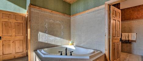 A bathroom with a freestanding bathtub, wooden doors, and tiled walls.