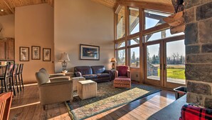 A spacious living room with a large window, a fireplace, and a cozy seating area. - North Shore Cabin w/ Fire Pit By Gooseberry Falls! (Two Harbors)