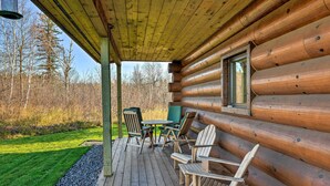 A wooden cabin with a deck, outdoor seating, and a window overlooking a forested area. - North Shore Cabin w/ Fire Pit By Gooseberry Falls! (Two Harbors)