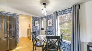 A kitchen with a stainless steel refrigerator, a dining table with chairs, and a window with curtains. - Camp-style Cabin Near Pigeon Forge: Fire Pit, Deck (Sevierville)