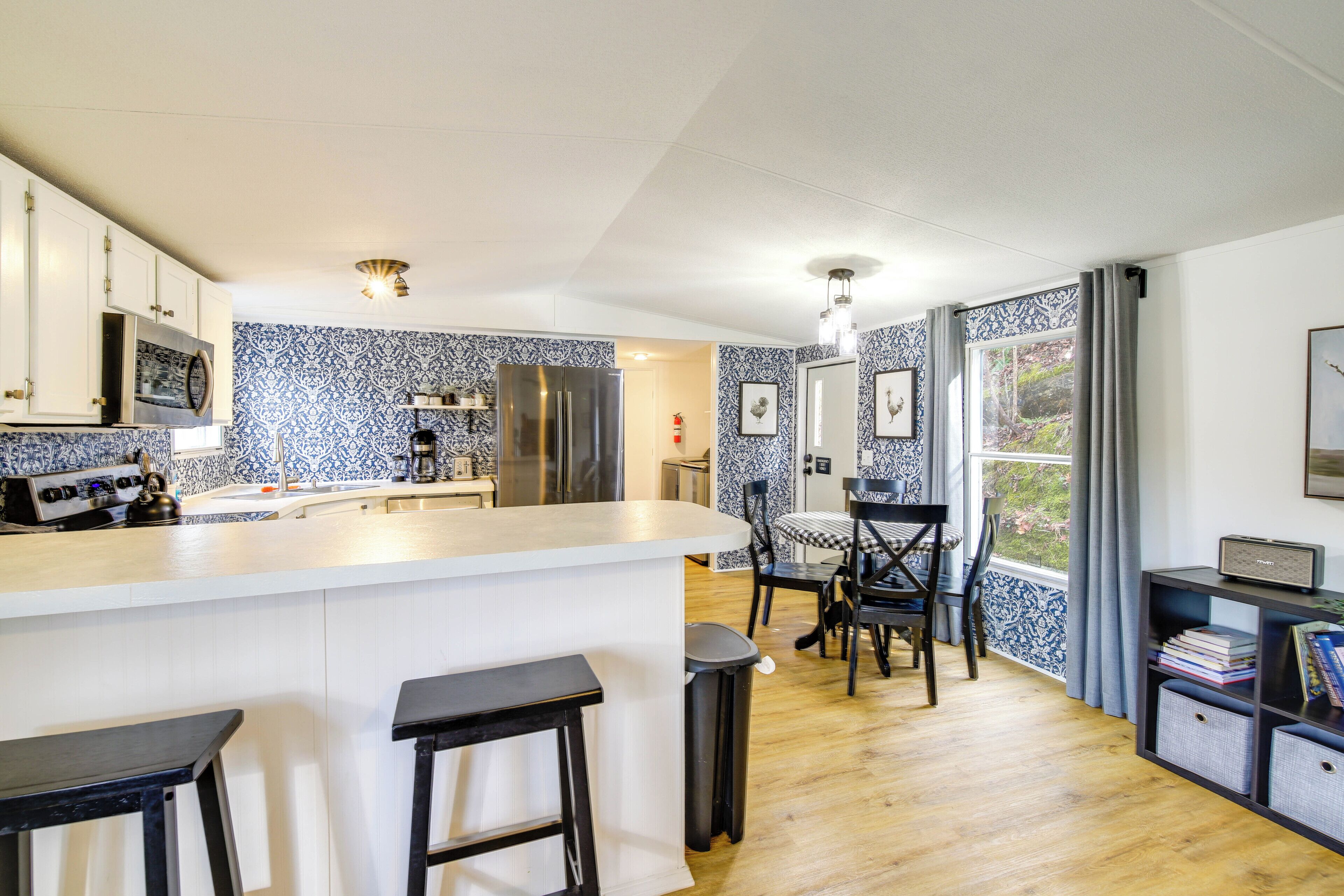 A modern kitchen with a central island, bar stools, and a dining area with chairs.