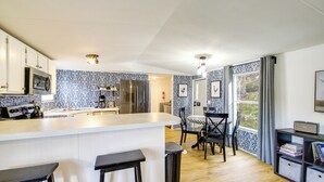 A modern kitchen with a central island, bar stools, and a dining area with chairs. - Camp-style Cabin Near Pigeon Forge: Fire Pit, Deck (Sevierville)