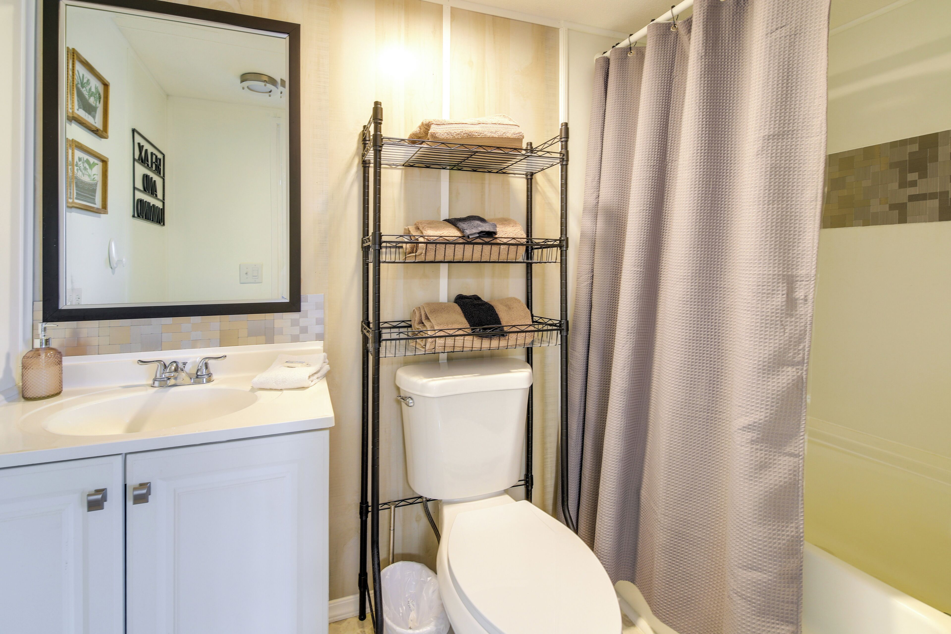 A bathroom with a white sink, a mirror, a toilet, and a shower curtain.