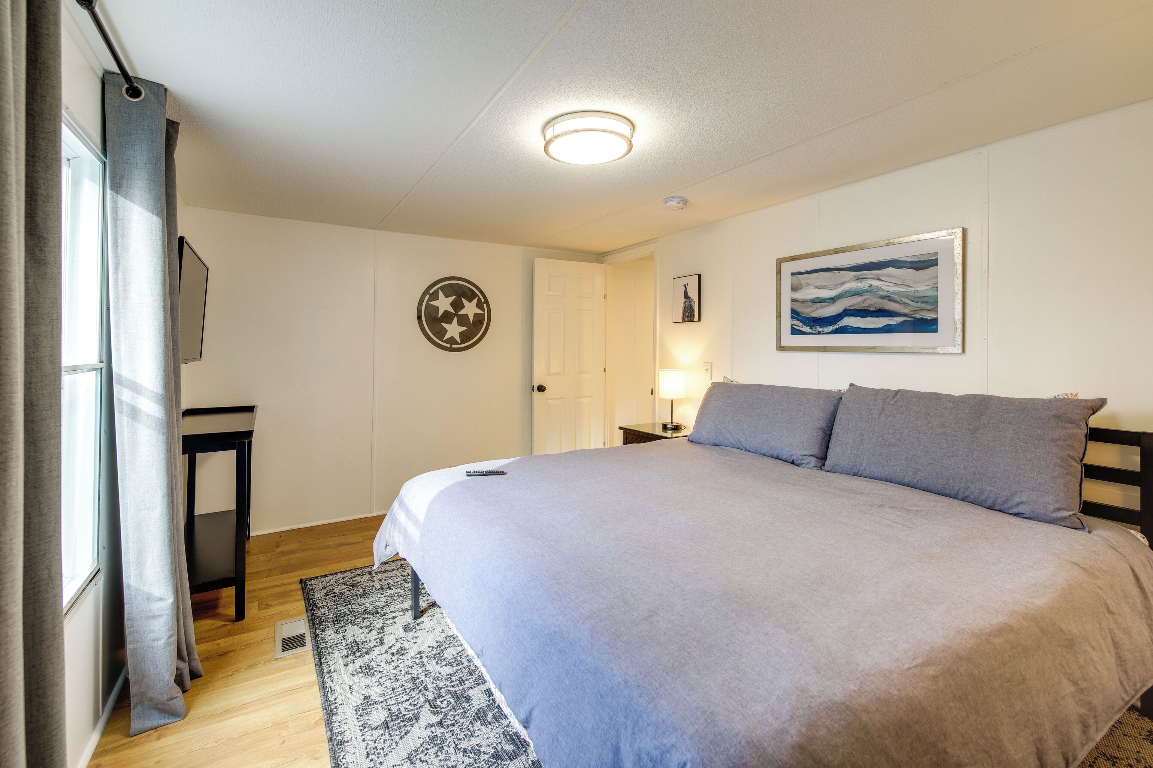 A bedroom with a large bed, a bedside table, a lamp, and a door.
