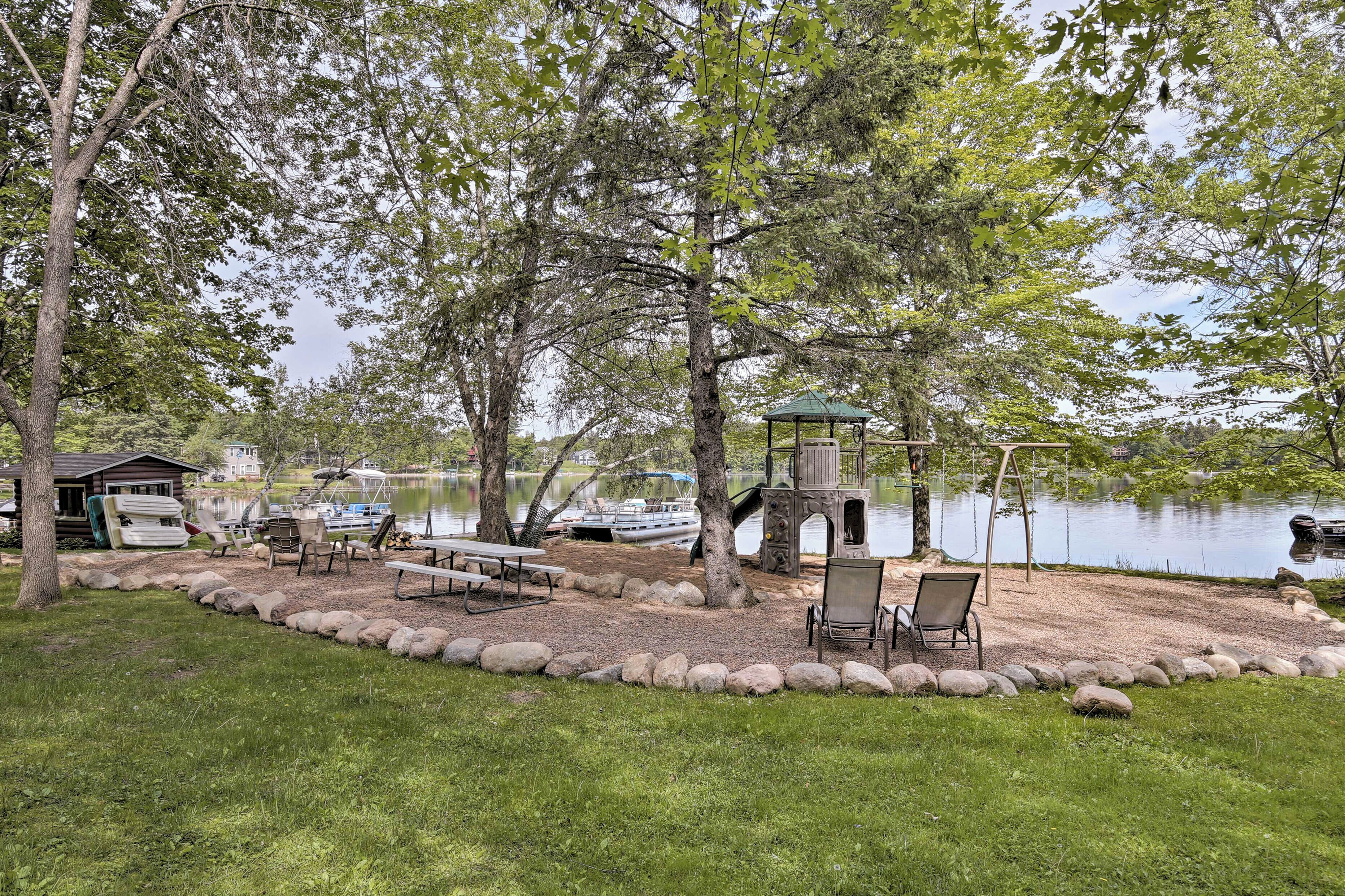 Un parc au bord du lac, équipé de tables de pique-nique, d’une balançoire et d’un kiosque.
