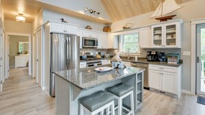 A modern kitchen with a central island, stainless steel appliances, and white cabinetry. - Oceanfront Prospect Harbor House w/ Deck, View (Prospect Harbor)