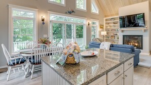 A spacious kitchen with a large island, white cabinetry, and a fireplace. - Oceanfront Prospect Harbor House w/ Deck, View (Prospect Harbor)