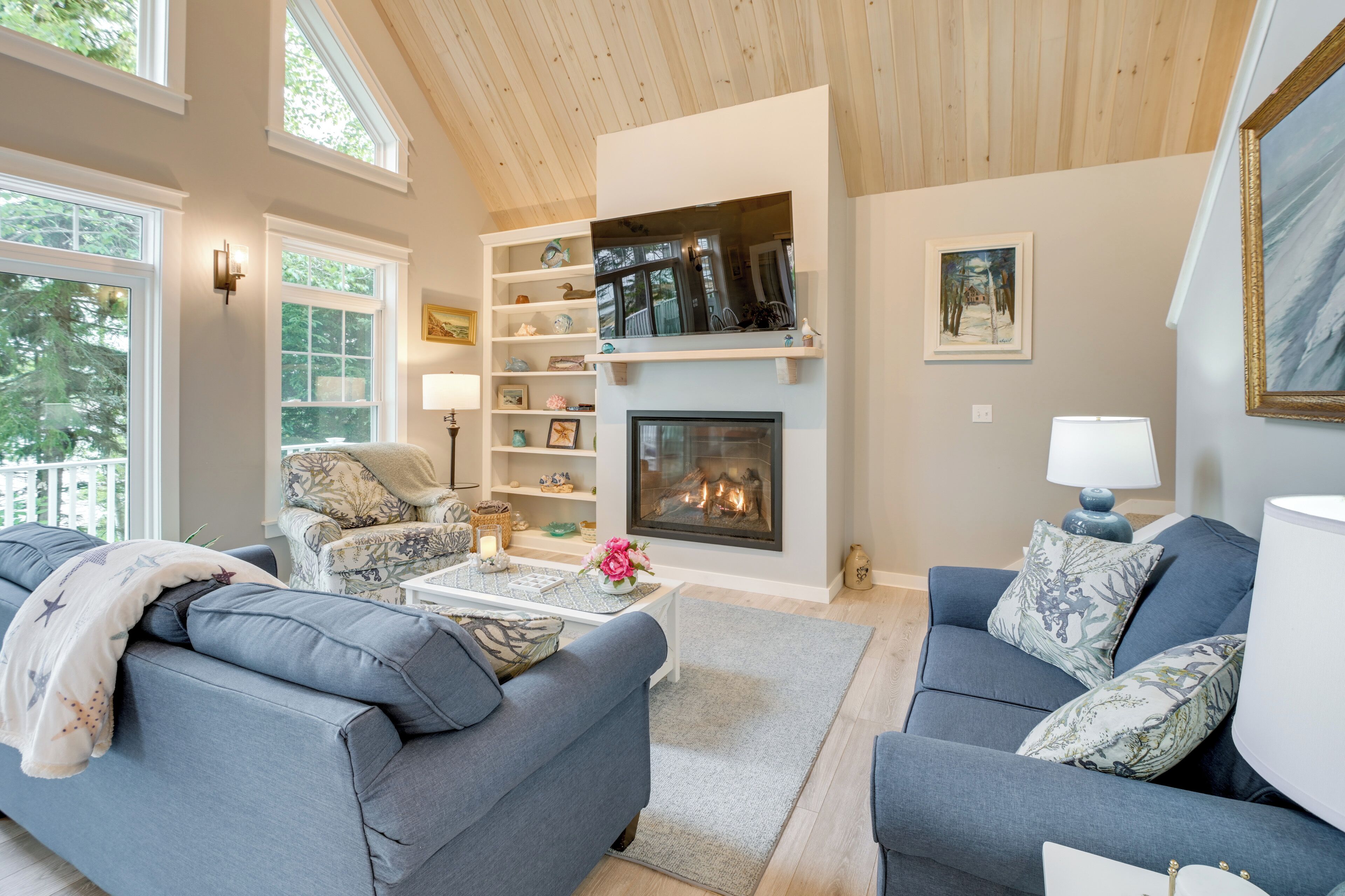 A living room with a fireplace, sofas, a coffee table, and a bookshelf.