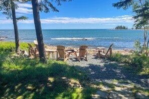 A beachside seating area with chairs and tables, overlooking the ocean. - Oceanfront Prospect Harbor House w/ Deck, View (Prospect Harbor)
