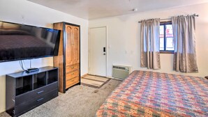 A bedroom with a bed, a TV, a wardrobe, a window with curtains, and a radiator. - Loveland Vacation Rental - 1 Mile to Lake! (Loveland)