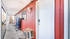A corridor with a red building, a white door, and a small air conditioning unit. - Loveland Vacation Rental - 1 Mile to Lake! (Loveland)