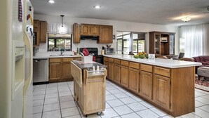 A kitchen with wooden cabinets, a central island, and a dishwasher. - Spacious Central Florida Home: Family Friendly! (Longwood)