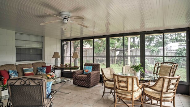 A sunlit patio with a sofa, armchairs, and a dining table. - Spacious Central Florida Home: Family Friendly! (Longwood)