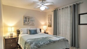 A neatly arranged bedroom with a bed, bedside lamps, a ceiling fan, and curtains. - Spacious Central Florida Home: Family Friendly! (Longwood)
