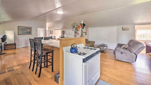 A spacious kitchen with a white stove, wooden chairs, and a dining table. - Loft Unplugged w/ Outdoor Space in Amish Country! (Middlefield)