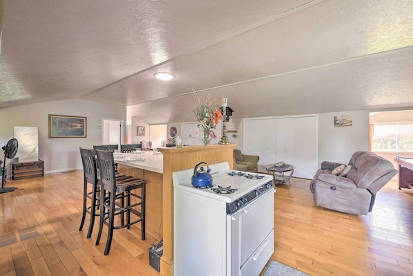 A spacious kitchen with a white stove, wooden chairs, and a dining table.
