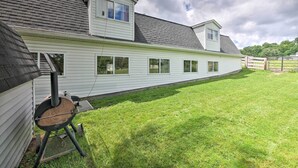 A house with a large attached garage, a covered outdoor area, and a well-maintained lawn. - Loft Unplugged w/ Outdoor Space in Amish Country! (Middlefield)