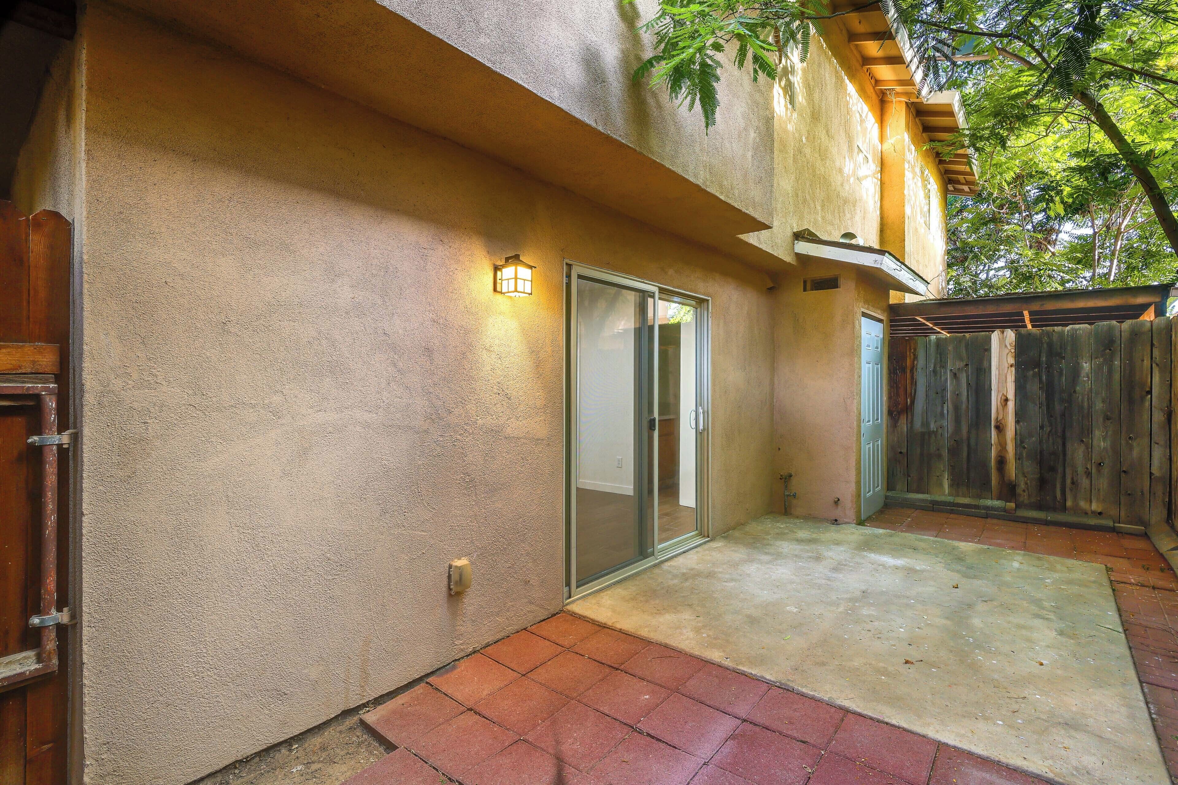 A patio area with a concrete floor, a sliding glass door, and a wooden fence.