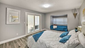 Une chambre avec un grand lit, une fenêtre avec des stores et une porte-fenêtre coulissante.