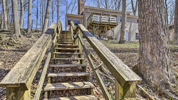 Una scala in legno conduce a una casa con veranda, immersa nel verde.