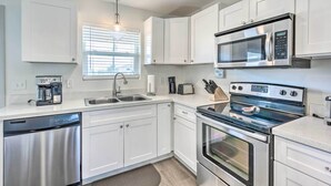 A modern kitchen with white cabinets, stainless steel appliances, and a dishwasher. - Mexico Beach Getaway w/ Balcony & Ocean Views! (Port St. Joe)