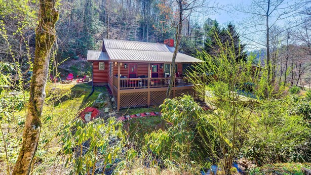 Une cabane dotée d’une terrasse, entourée d’une forêt.
