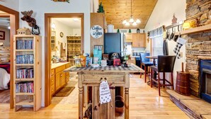 Une cuisine chaleureuse avec des meubles en bois, un panneau indiquant un coin café et une cheminée en pierre au style rustique.