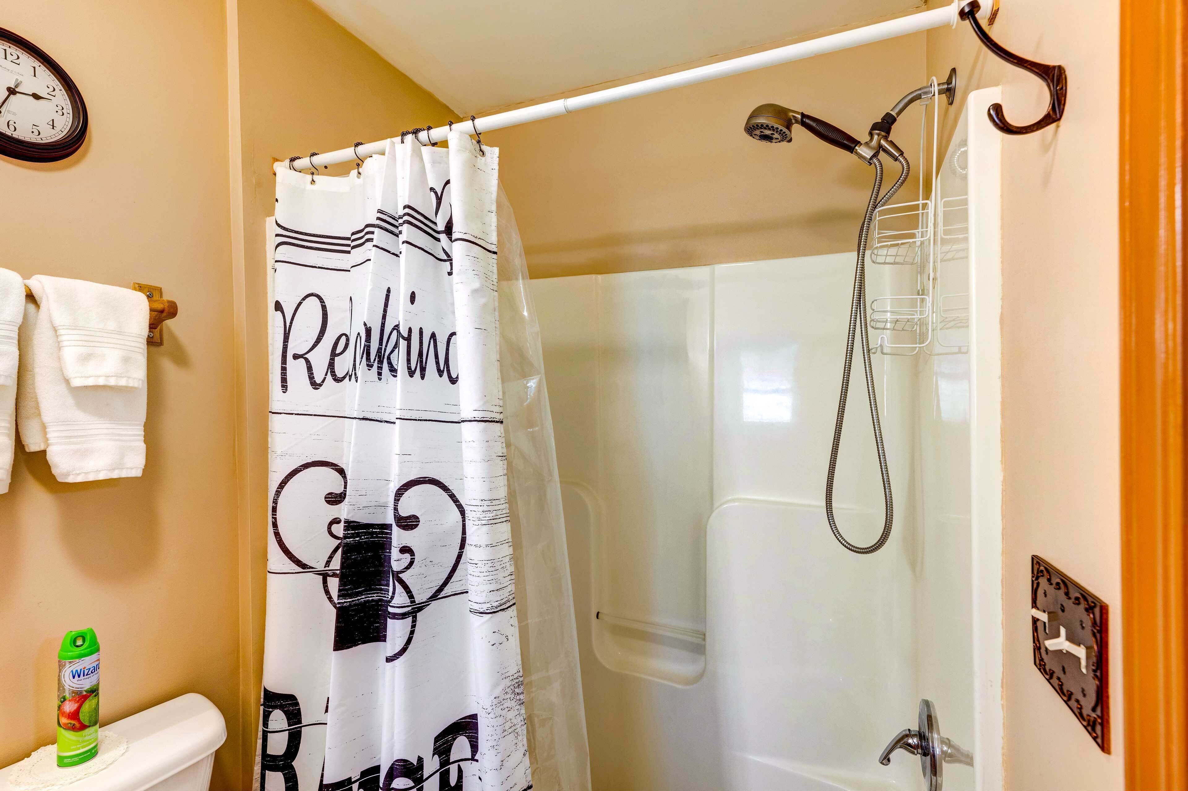 A bathroom with a shower, a toilet, a towel rack, and a clock on the wall.