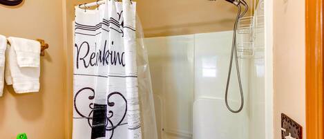 A bathroom with a shower, a toilet, a towel rack, and a clock on the wall.