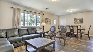 A living room with a sectional sofa, a coffee table, and a dining area with chairs and a table. - Ideally Located Glen Cove Apartment! (Glen Cove)