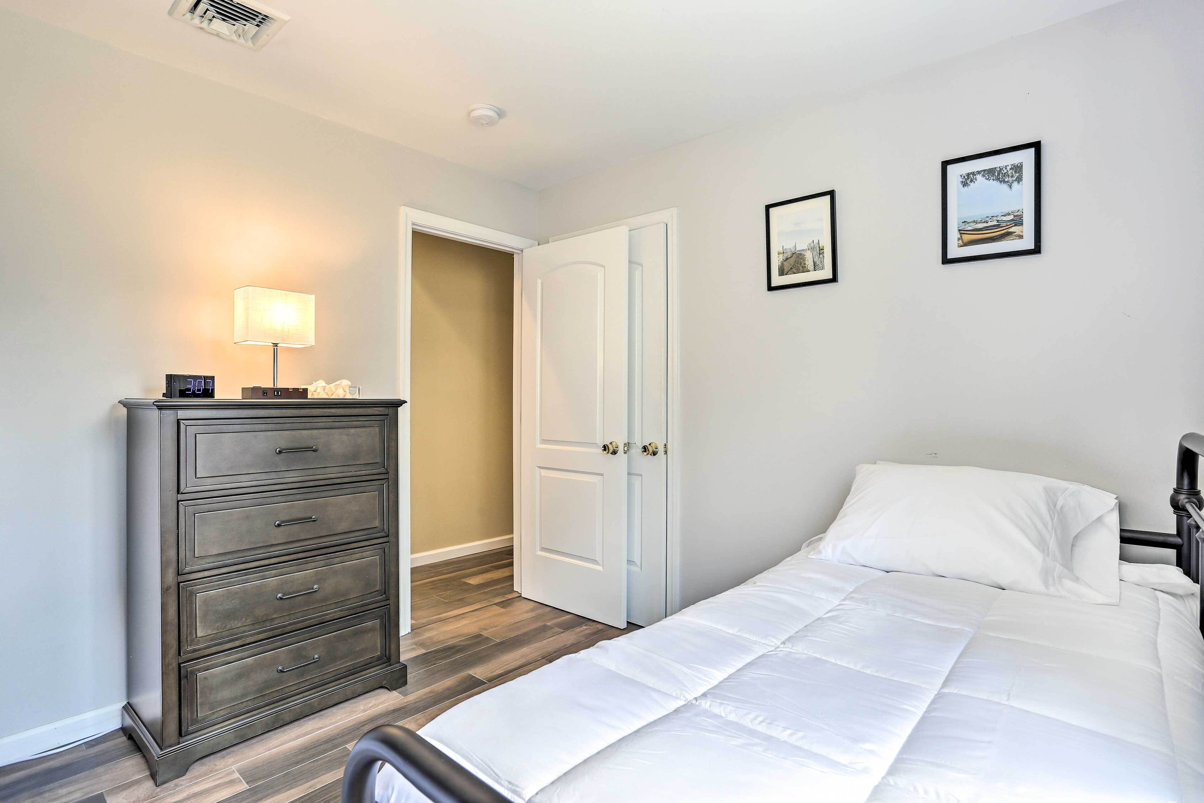 A bedroom with a bed, a dresser, a lamp, and two framed pictures on the wall.