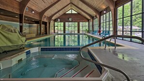 Une piscine intérieure avec des poutres en bois et de grandes fenêtres.