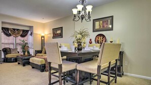 A dining area with a dark wooden table, beige upholstered chairs, and a chandelier. - Maryland Vacation Rental Near Baltimore (Perry Hall)