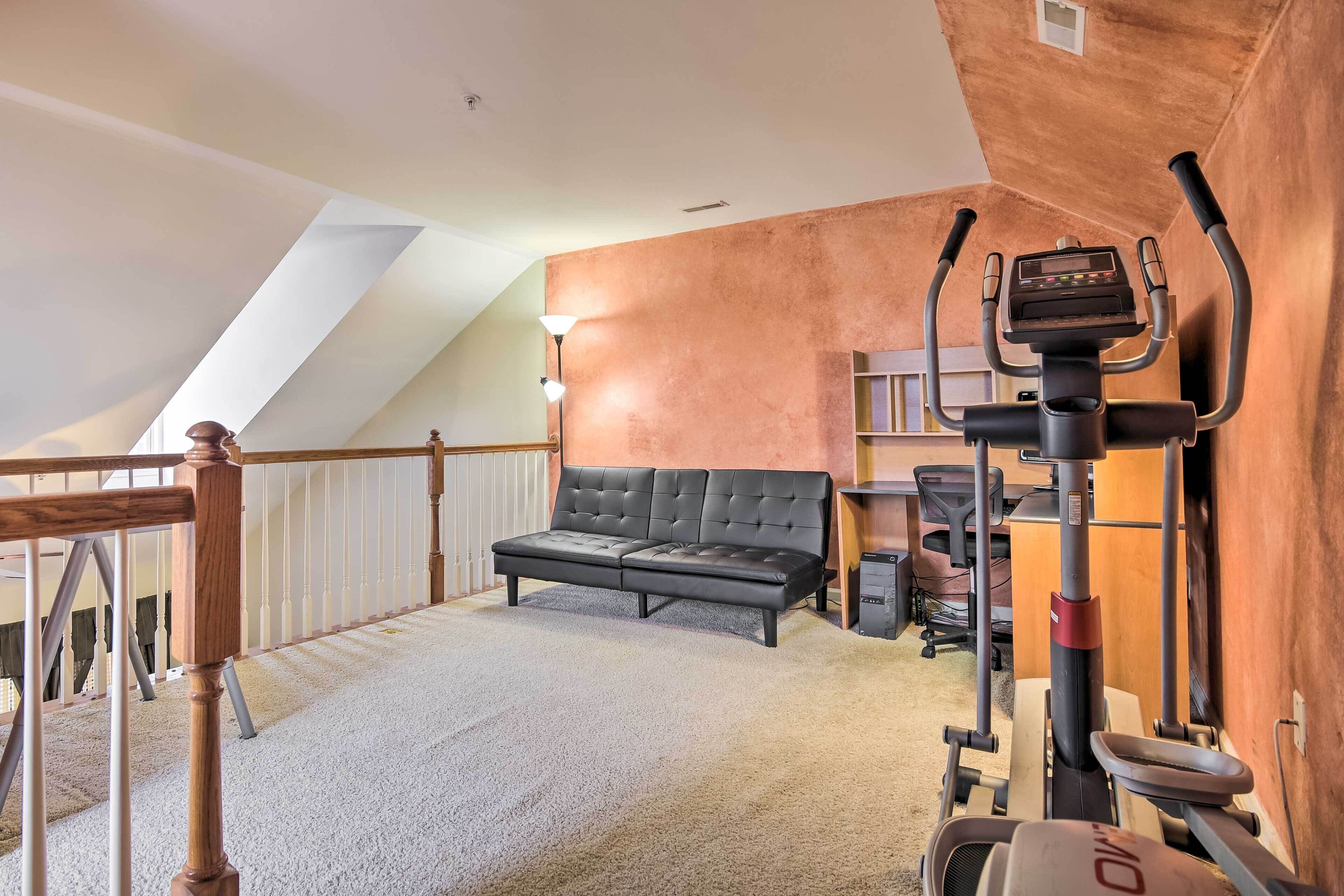 Ein Heimfitnessraum mit Laufband, Sofa und Treppe.