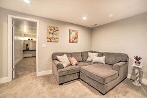 A living room with a gray sectional sofa, two wall-mounted paintings, and a potted plant. - Pocatello Retreat ~ 3 Mi to Downtown! (Pocatello)
