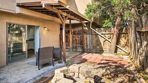 Un patio con una pérgola, una silla de mimbre y un sendero de ladrillos.
