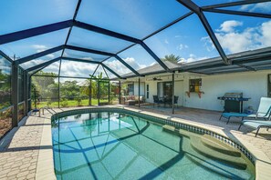 A covered outdoor swimming pool with a glass ceiling, surrounded by patio furniture and a barbecue area. - Screened Porch & Heated Pool: Cape Coral Home (Cape Coral)